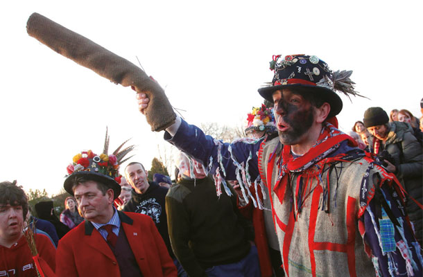 革の筒を掲げる参加者の男性。華やかな衣装と激しい競技のギャップが大きい